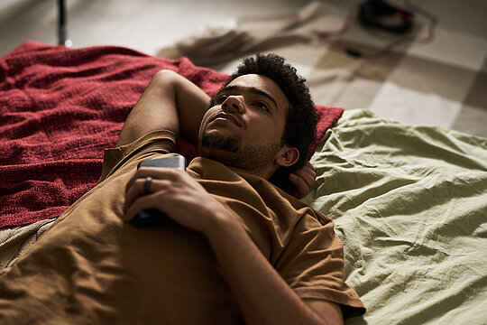 Guy staying alone with his thoughts Liggende jongen met telefoon