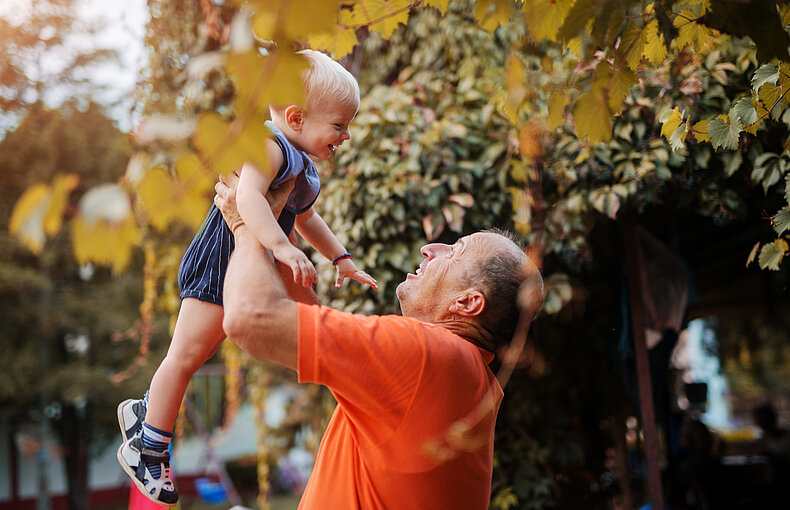 Love on first sight. Proud grandfather playing with is grandson in a backyard, lifting him in the air. afbeelding Contact