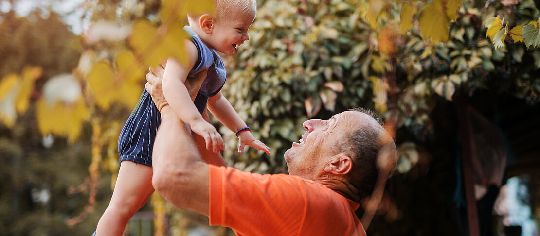 Love on first sight. Proud grandfather playing with is grandson in a backyard, lifting him in the air. Love on first sight. Proud grandfather playing with is grandson in a backyard, lifting him in the air.
