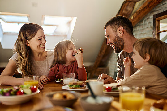 Young family talking during breakfast at dining table. Familie van vader, moeder, dochter en zoon aan de eettafel aan het eten