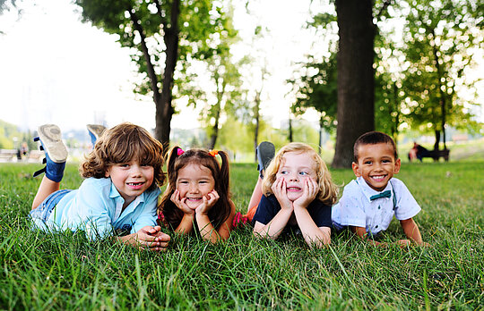 friends of preschool kids playing lying on the grass in the Park on a summer day